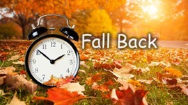 Daylight Savings Fall Back. An alarm clock in a field of leaves.