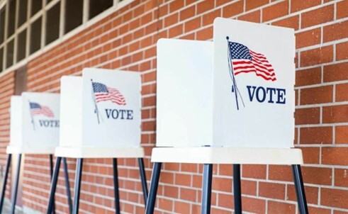 Voting booths in a row in front of a brick wall. 