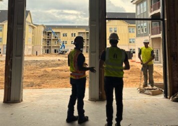 A group of men in safety vests and helmets standing in a building under construction.