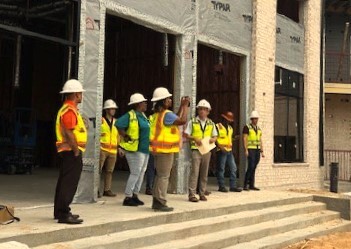 People in construction gear outside a building being renovated.